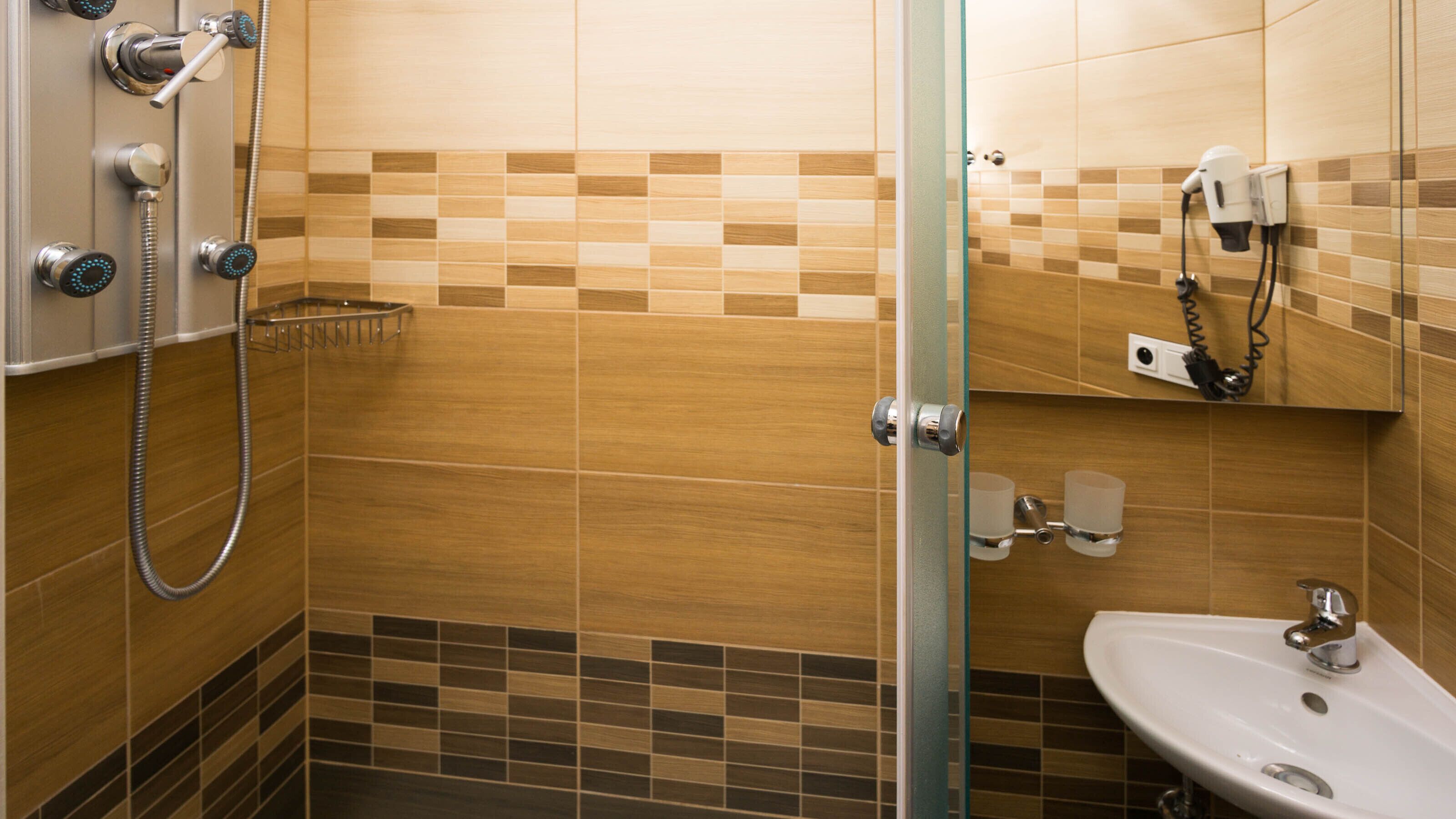 Un baño con ducha, lavabo y perchero para toallas.