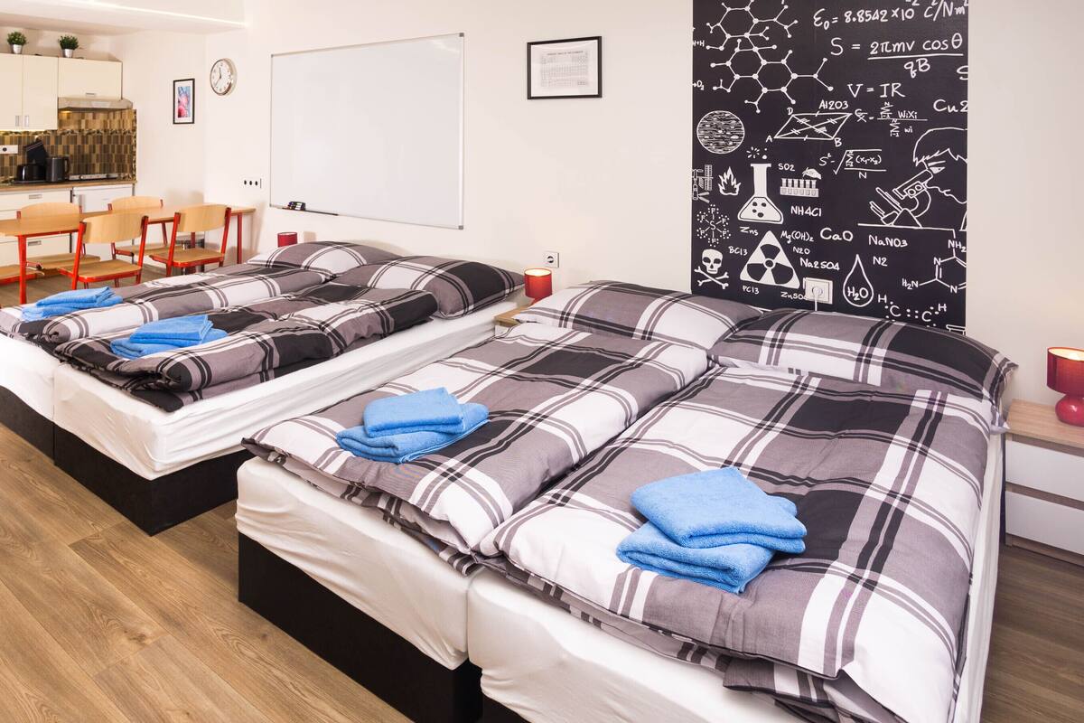 Ein Hotelzimmer mit zwei Betten, einer Küchenzeile und einem Esstisch.