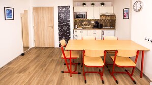 Een moderne keuken met een houten tafel en rode stoelen, een magnetron en een klok aan de muur.