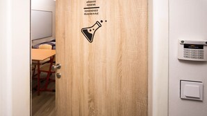 Een houten deur met een bordje 'scheikundelokaal', een keypad en een lichtschakelaar.