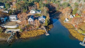 A residential area with houses along a river, featuring a dock and a bridge. - Coveshead. Dramatic waterfront designer cottage. (Harpswell)