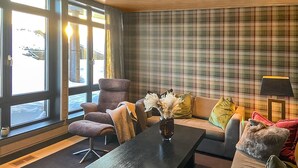 A modern living room with a large window, a plaid-patterned wall, and a sofa with a vase of dried flowers. - Amazing apartment in Noresund with WiFi (Noresund)