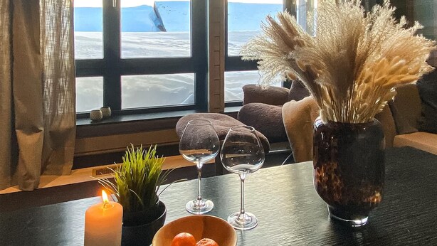 A cozy seating area with a view of the sea, a candle, a vase with pampas grass, and two wine glasses on a table. - Amazing apartment in Noresund with WiFi (Noresund)