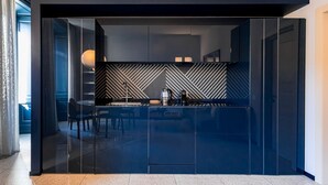 A modern kitchen with a glass partition, a herringbone-patterned backsplash, and a dining area with chairs. - Sky Suite - My Home in Como (Como)
