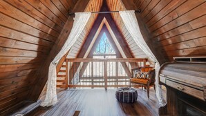 Une chambre confortable située sous les toits, avec des murs en bois, un plafond en pente, une fenêtre offrant une belle vue, un lit, une commode et un petit tapis.