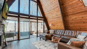 Un loft spacieux avec un grand plafond en bois, un canapé d’angle en cuir et une cheminée en pierre.
