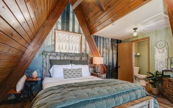 A cozy attic bedroom with a sloped ceiling, a bed with a green quilt, a nightstand with a salt lamp, and a rustic decor.