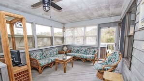 A covered porch with wicker furniture, a glass table, and a television on a stand. - Oceanside, Hot Tub, Rec Room, OD1, The Sandy Dune (Duck)