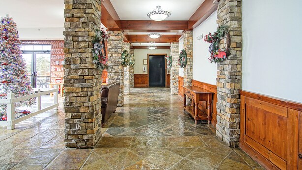 A stone-walled hallway with a fireplace, wooden benches, and a Christmas tree. - Rimfire 259 : Walking distance to village,slopes, 1 Br Sleeps 4 (Snowshoe)