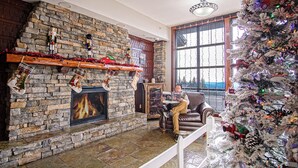 A cozy living room with a stone fireplace, a Christmas tree, and festive decorations. - Rimfire 259 : Walking distance to village,slopes, 1 Br Sleeps 4 (Snowshoe)