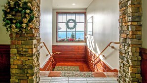 A staircase with stone walls, a wooden handrail, and a view through a window with a wreath. - Rimfire 259 : Walking distance to village,slopes, 1 Br Sleeps 4 (Snowshoe)