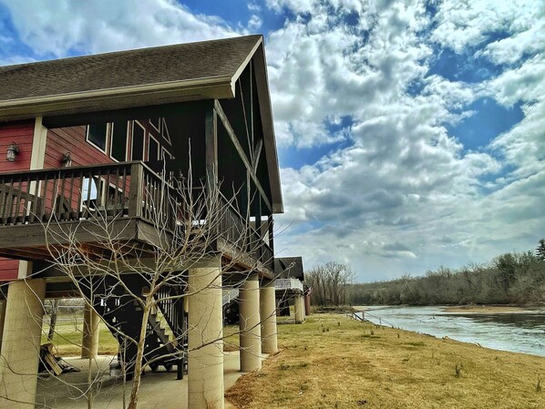 A building with a balcony, a river in the background, and a cloudy sky.