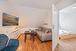 A modern living room with a sofa, a coffee table, and a TV mounted on the wall.