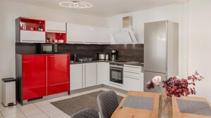 Eine moderne Küche mit weißen Schränken, einem roten Kühlschrank und einem eingebauten Backofen.