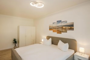 A bedroom with a bed, bedside tables, a wardrobe, and a wall-mounted artwork.