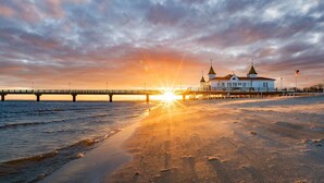 Ein Strand mit einem Steg und einem Gebäude mit zwei Türmen.
