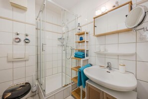 A bathroom with a glass-enclosed shower, a white sink, and a mirror.