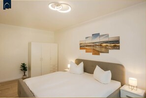 A bedroom with a bed, bedside tables, a wardrobe, and a wall-mounted artwork.