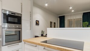 Una cocina moderna con electrodomésticos de acero inoxidable, encimeras de madera y armarios blancos.