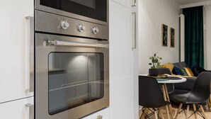 Una cocina moderna con horno integrado y comedor con mesa redonda y sillas.