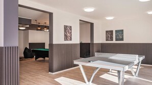 A room with a ping pong table, a pool table, and a billiards table.