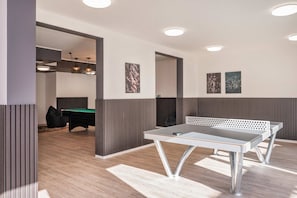 A room with a ping pong table, a pool table, and a billiards table.