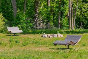 A grassy field with two wooden benches, a metal fence, and a wooden structure in the background.