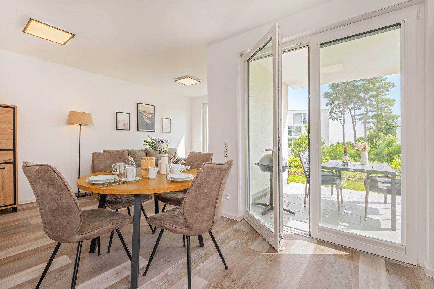 A dining area with a round table, chairs, and a view through a glass door to an outdoor patio.