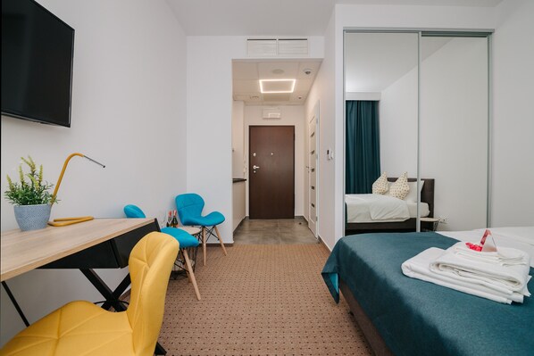 Cozy retreat with a comfortable bed, desk, and TV, perfect for a relaxing stay.
