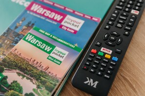 A travel guidebook titled 'Warsaw' and a remote control with buttons including 'Netflix'. - Varsovia Comfort 930 (Warszawa)