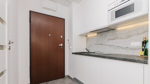 Een moderne keuken met witte kasten, een marmeren spatwand en een ingebouwde oven.