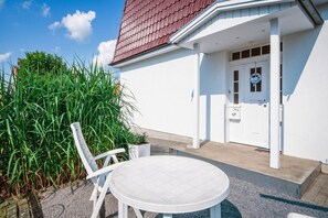 Ein weißes Gebäude mit rotem Dach, einer Haustür und einem kleinen Veranda-Bereich.