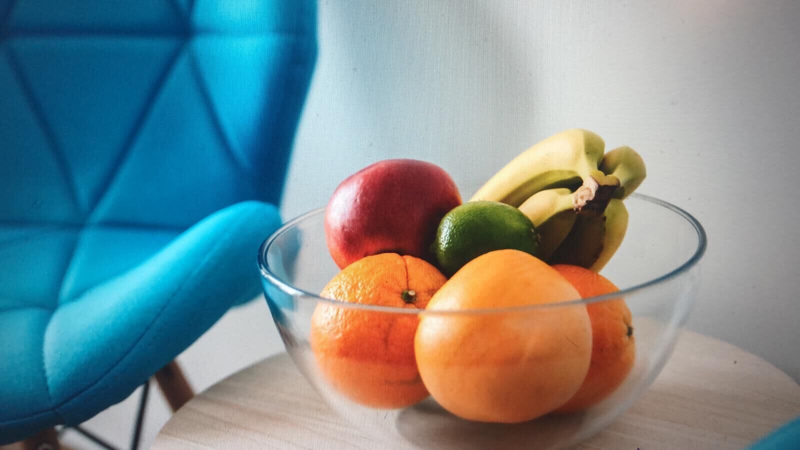 A clear glass bowl containing various fruits on a table.