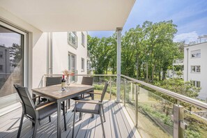 Un balcon avec une table, des chaises et une bouteille de vin.