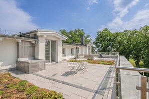 Un bâtiment moderne doté d’un toit plat, d’un espace extérieur aménagé pour s’asseoir et d’un petit jardin.