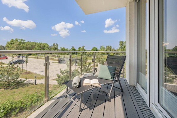 A balcony with a chair, a table, and an umbrella.