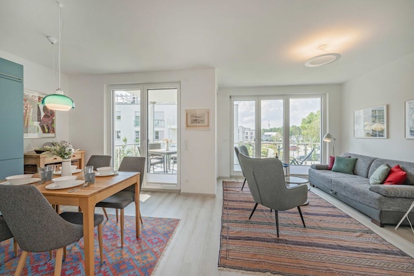 A modern apartment with a dining area, a sofa, and large windows.
