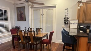 Ein Essbereich mit Holztisch und Stühlen, einem Deckenventilator und einer Küche mit Schränken und Arbeitsplatte.