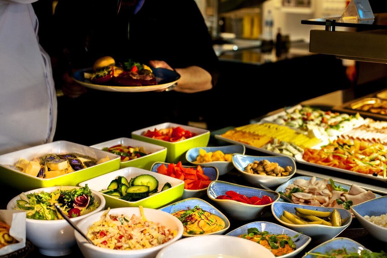 Un buffet proposant une variété de plats, notamment des salades, des viandes et des légumes.