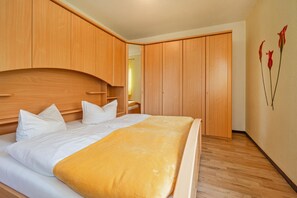 Un dormitorio con cama, armario de madera y una pared decorada con motivos florales.