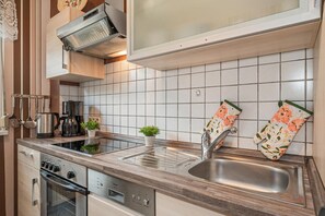 A modern kitchen with a stainless steel sink, a built-in oven, and a coffee maker.