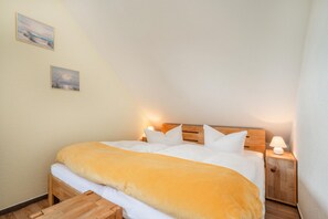 Un lit simple avec une tête de lit en bois, une literie blanche et deux lampes de chevet.