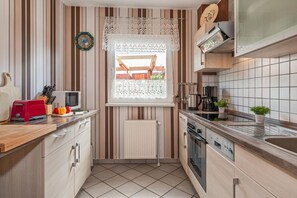 A compact kitchen with a window, a red toaster, a microwave, a coffee maker, and a sink.