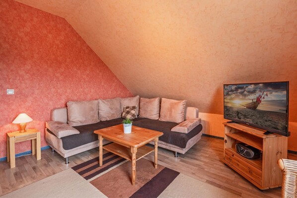 A cozy living room with a sofa, a coffee table, a TV, and a wooden cabinet.