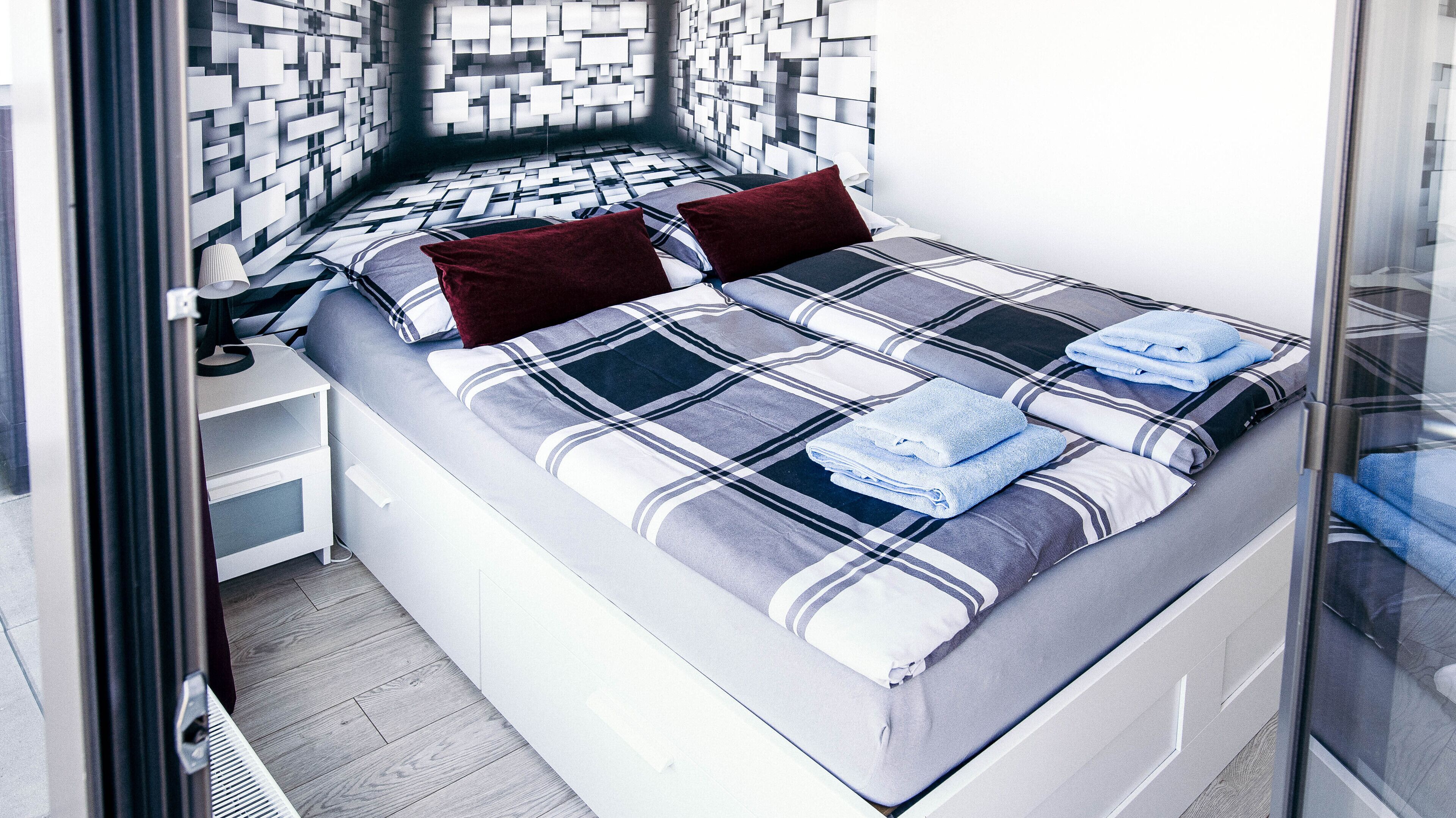 Un dormitorio moderno con cama, almohadas y mesita de noche.
