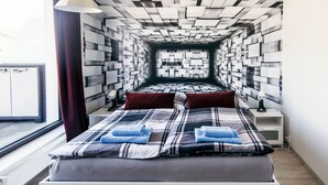 A modern hotel room with a geometric patterned wall, a bed with plaid bedding, and a nightstand with a lamp. - Cozy Apartment with Big Terrace - Karlín (Prague)