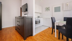 A modern kitchen with white cabinets, a built-in oven, and a dining area with a table and chairs.