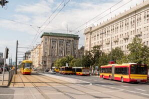 Une ligne de tram avec des tramways et un immeuble doté de nombreuses fenêtres et de balcons.