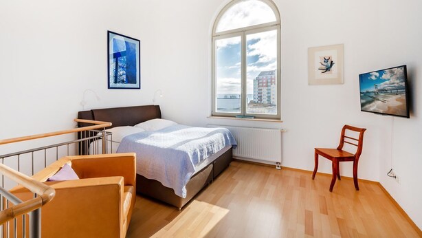 Een slaapkamer met een bed, een raam, een stoel en een televisie.