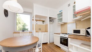 A modern kitchen with white cabinets, a wooden dining table, and a built-in microwave. - Royal Route Apartment for 10 people (Warszawa)